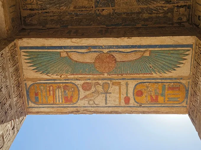 Painted winged sun disk and cartouches on an ancient Egyptian temple ceiling